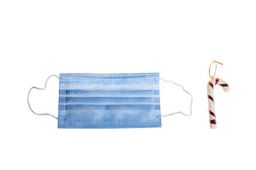 Christmas decoration on white background of candy cane and protective medical face mask for Covid-19.