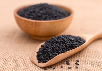 Black sesame seeds in wooden spoon.