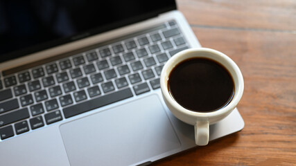 Close - up shot of White coffee cup placed on the laptop.