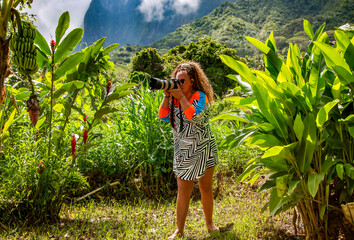 Pretty woman with curly hair taking photographs with moderne camera on Bora Bora island, French...