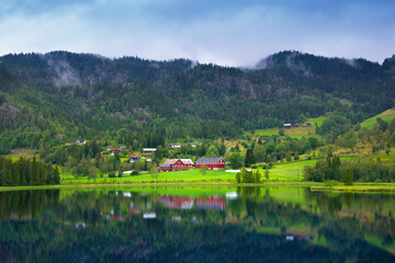 Fototapeta na wymiar Beautiful Nature Norway, natural landscape. Village in the valley. Norwegian landscape. Beautiful fjords. Cloudy and rainy day. Lakes, mountains and classical Scandinavian houses
