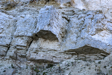 sandy-gypsum cut of the earth in quarry for the extraction of gypsum. Mountain textures of different soil layers with deposits of sand, clay, gypsum, quartz and gypsum ore, after erosion.