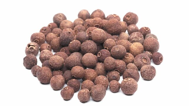 Close-up view of a heap of allspice berries, isolated on white, seamless loop rotation