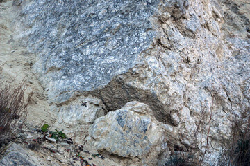 sandy-gypsum cut of the earth in quarry for the extraction of gypsum. Mountain textures of different soil layers with deposits of sand, clay, gypsum, quartz and gypsum ore, after erosion.