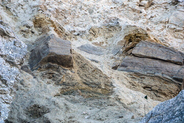 sandy-gypsum cut of the earth in quarry for the extraction of gypsum. Mountain textures of different soil layers with deposits of sand, clay, gypsum, quartz and gypsum ore, after erosion.