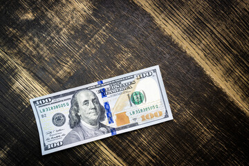 textured background of one hundred dollar bill with a portrait of us President Franklin in orange, red and black colors. blur, defocus.