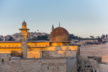 Siliver dome of Al-Aqsa Mosque under sunset in the evening, built on top of the Temple Mount, known as Haram esh-Sharif in Islam and al-Fakhariyya Minaret and wall of old city of Jerusalem, Israel.