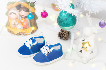Baby shoes under the christmas tree. The miracle of life, pregnancy present, birth celebration and gestation during christmas.