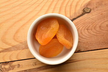 Bright orange natural dried apricots, close-up, on a wooden table.