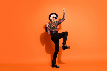 Full size photo of smiling excited crazy hipster old lady raise fists in victory isolated on orange...