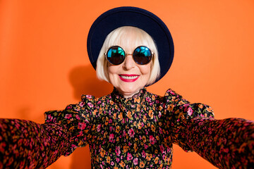 Portrait of happy smiling cheerful positive grandmother take selfie wear sunglasses isolated on orange color background