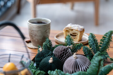 Close up of cake  and cup of tea with steam and candle on a coffee table. Breakfast over sofa in winter morning. Cozy holiday winter concept