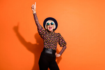 Photo of cheerful smiling crazy happy positive old woman dance point finger copyspace isolated on orange color background