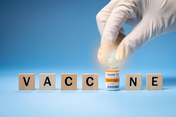 Promising Covid-19 Vaccine concept. Hand of a researcher take a 2019-nCov vaccine vial with wooden...