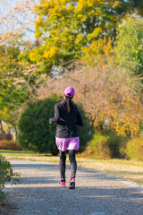Fototapeta premium 秋の公園でジョギングしている若い女性の姿