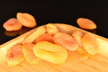 Bright golden organic dried apricots, close-up, isolated on black.