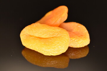 Bright golden organic dried apricots, close-up, isolated on black.