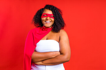 spanish woman in eye mask and superhero cloak in red studio background