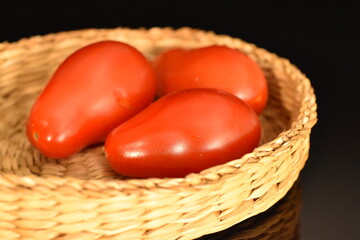 Ripe red tomatoes in the shape of a strawberry, close-up, isolated on black.