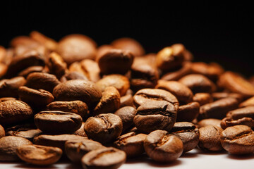 Macro view of roasted fresh Arabica coffee beans isolated on black background, extreme close up photo of fresh coffee beans on dark background.