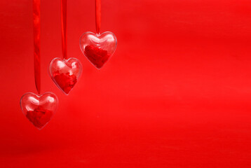 Transparent hearts with red confetti inside on red background. Valentine's day greeting card concept. Banner, copy space