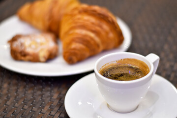 Espresso coffee in a white cup with bread is background.
