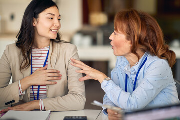 Young female colleagues discussing the job in the company. People, job, company, business concept.