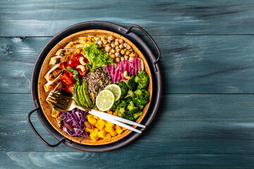 Buddha bowl with kale salad, chicken fillet, quinoa, avocado, pumpkin, tomato, broccoli, red cabbage, chickpea, watermelon radish, fresh lettuce salad, nuts