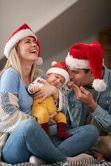 Fototapeta premium Young parents are so much in love with their baby on New Year eve at home. New Year, family concept, together, love