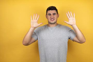 Young handsome man wearing a casual t-shirt over isolated yellow background smiling confident and happy showing number ten with fingers