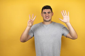 Young handsome man wearing a casual t-shirt over isolated yellow background smiling confident and happy showing number eight with fingers