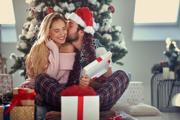 Obraz na płótnie Canvas Inlove couple sharing gifts on Chrismas morning; White Christmas concept