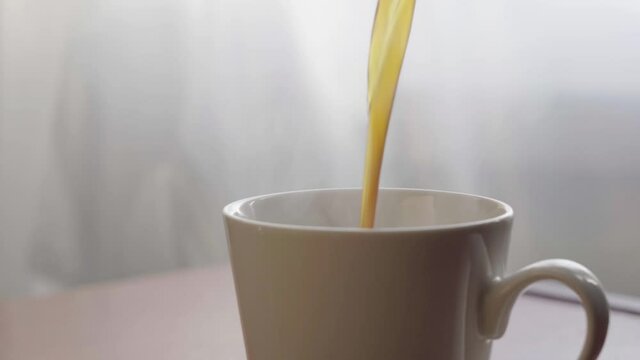 Pour black coffee into a mug from a coffee pot. Drink fresh coffee in the morning.