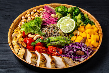 Fototapeta na wymiar Fresh salad. Bowl with fresh raw vegetables, chicken fillet, quinoa, avocado, chickpea, watermelon radish and nuts. Healthy food. buddha bowl