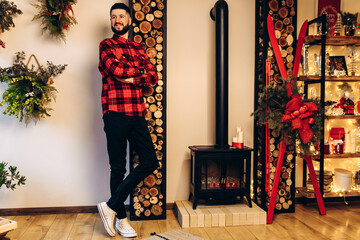 Christmas young man, in a red shirt, celebrates Christmas at home, in a stylishly decorated house before Christmas, Merry Christmas