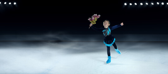 view of child figure skater on dark ice arena background