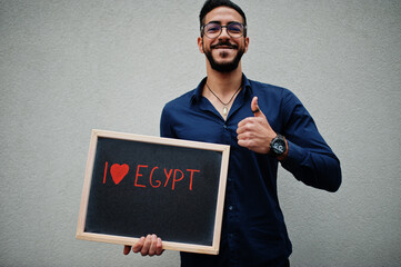 I love Egypt. Middle eastern man wear blue shirt, eyeglasses, hold board.