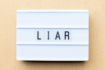 White lightbox with word liar on wood background