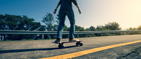 Fototapeta na wymiar Skateboarder riding skateboard on sunrise mountain peak