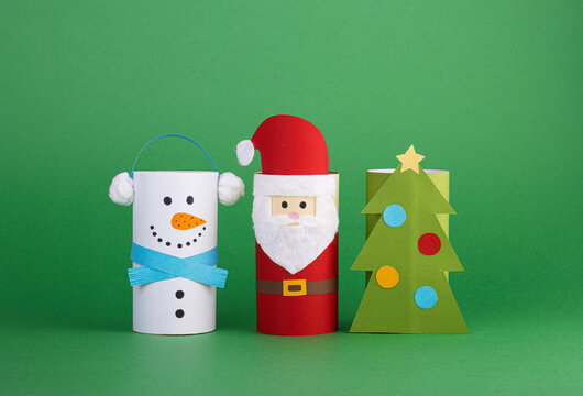 Christmas toys from a toilet tube roll on a green background. Santa, snowman and Christmas tree