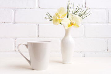 White coffee latte mug mockup with gentle yellow orchid in vase