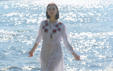 Fototapeta premium Young woman in white dress enjoys sea.