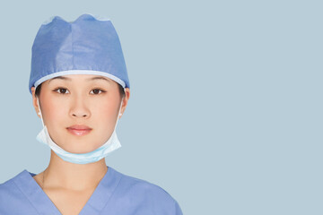 Close-up portrait of female surgeon over light blue background
