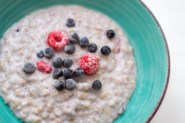 Oatmeal porridge in a plate with currant and raspberry berries. 
