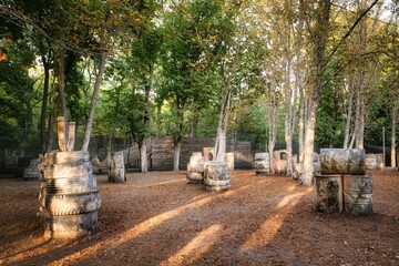 Old rusty barrels and damaged tires on a paintball base