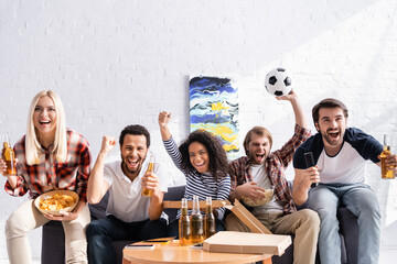 excited multicultural friends screaming and showing win gesture while watching football championship