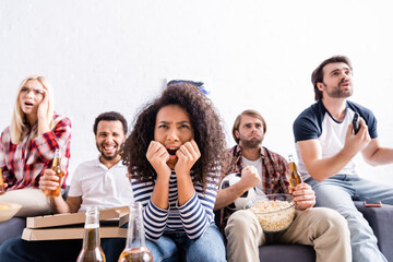 worried multicultural friends watching football championship at home
