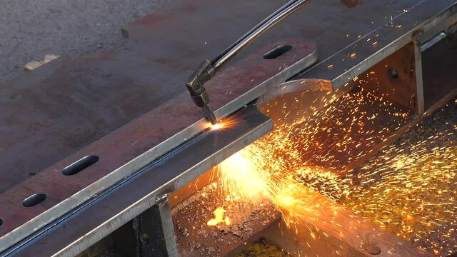 Worker using a Plasma cutter on Thick Metal plate.
