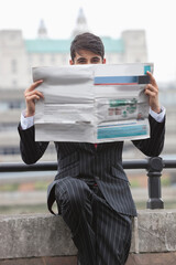 Portrait of a businessman holding newspaper in front of his face with St. Paul's Cathedral in the...