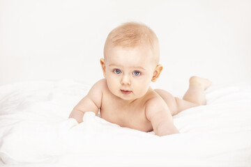 Cute baby boy smiling to the camera, lying on white background.